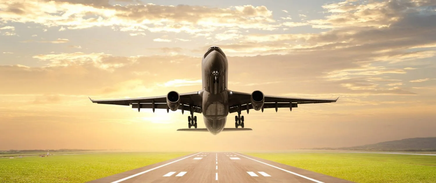 A passenger aircraft lifting off a runway at sunrise
